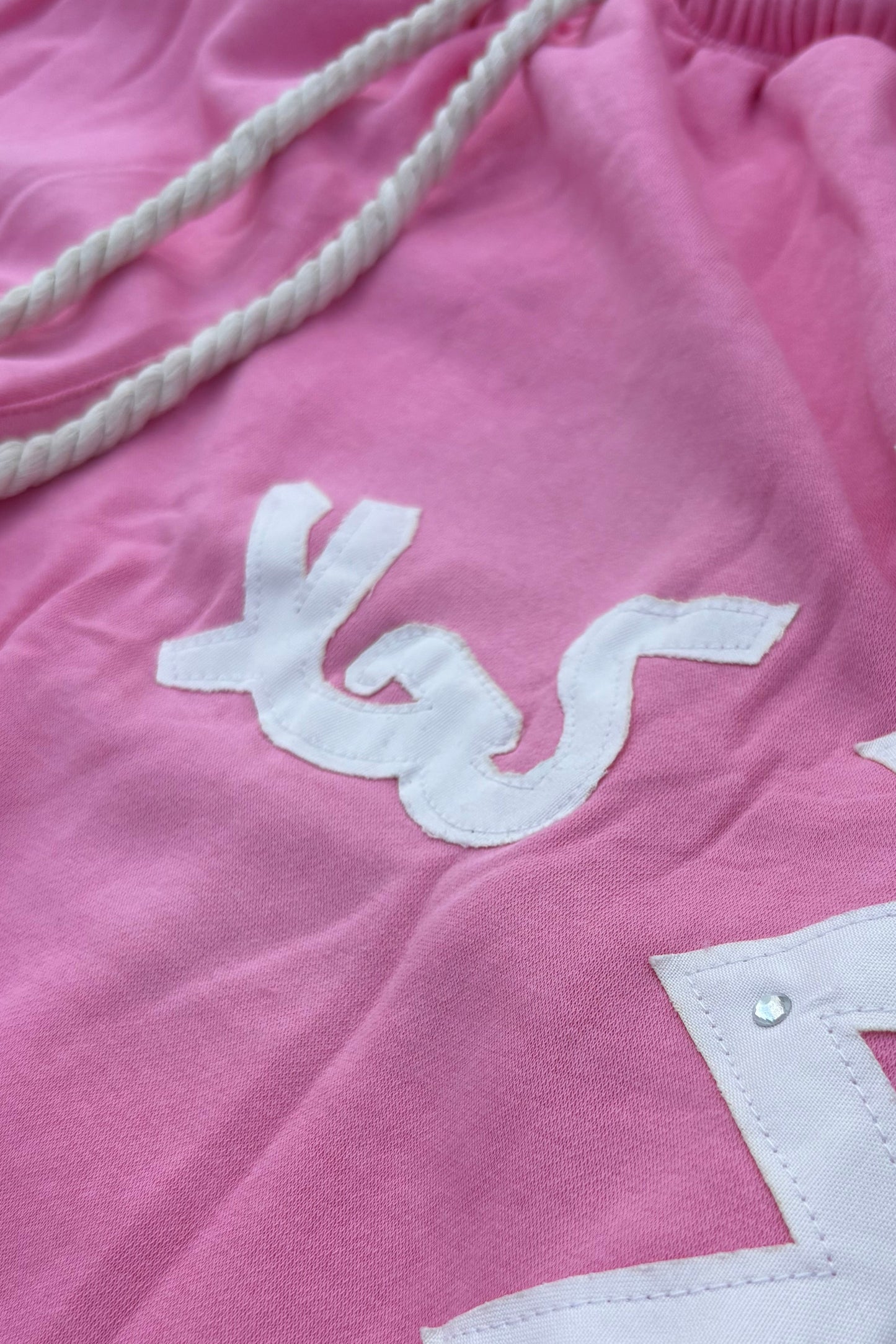 Pink shorts with white zigzag pattern on a textured surface